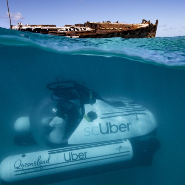 The ride-share submarine scUber, seen submerging near the shipwreck of HMAS Protector in the Great Barrier Reef.