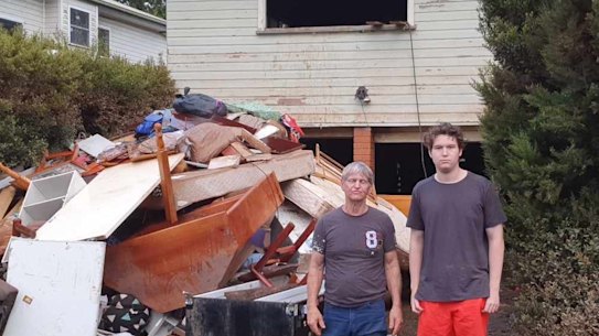 Joe Booker and son Benjamin outside their Lismore home that was destroyed in the floods. 
