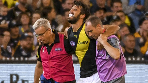 Tigers defender Alex Rance is helped from the field.