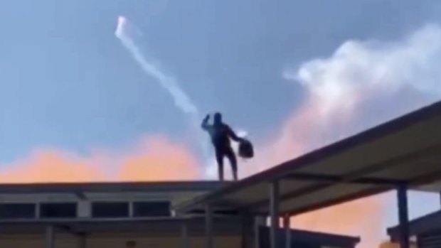 The individual on the roof of the school throwing a flare.