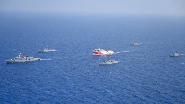 Turkey's research vessel, Oruc Reis, in red and white, is surrounded by Turkish navy vessels in the Mediterranean. 