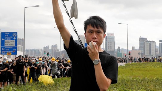 Pro-democracy lawmaker Roy Kwong speaks over a loud hailer to the police as he joins protesters in Hong Kong on Monday, July 1.