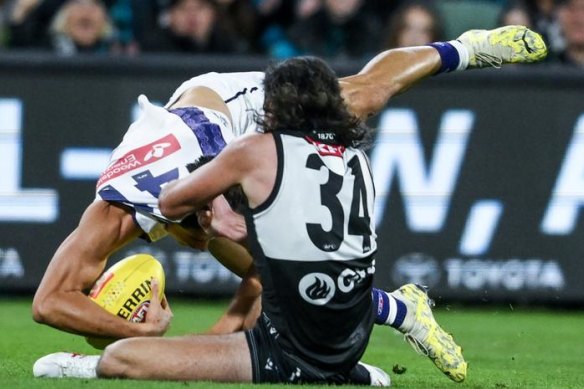 Bailey Banfield gets caught holding the ball by Lachie Jones.