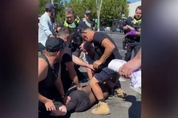 Police and bystanders detain Ahmed at the scene in Carlton on March 11, 2023.