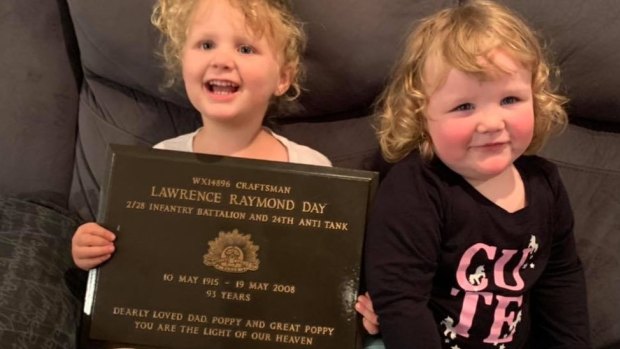 The great grand daughters, Emma and Aaliyah, of war veteran Lawrence Raymond Day holding his returned gravestone plaque. 
