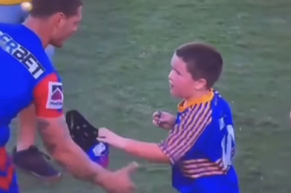 Awkward ... Kalyn Ponga appears to be brushed by a young fan who has no interest in his headgear