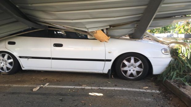 A car lays crushed underneath a gum tree, which fell in the Canberra suburb of Watson on Thursday.
