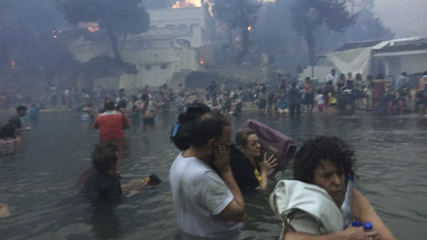 Dozens shelter in the sea as fire rips through the resort town. 