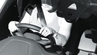While this driver is wearing their seatbelt correctly in this image, the phone should not be touching any part of their body.
