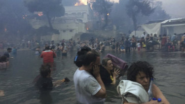 Dozens shelter in the sea off the "Silver Coast" beach in Mati, Greece as fire rips through the resort town on July 23.