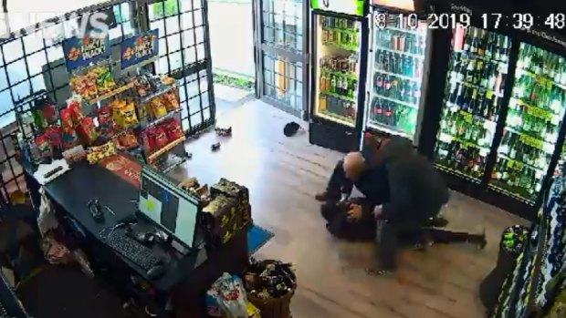 Men inside the store restrain one of the robbers.