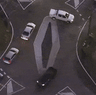 Aerial footage shows a ute doing a three-point turn to get around the diamond, while two other cars cut directly across the roundabout.