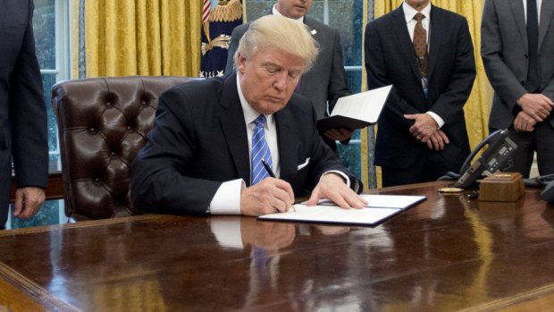 U.S. Donald Trump signing a document. The budget will fund research into gun violence for the first time in years.