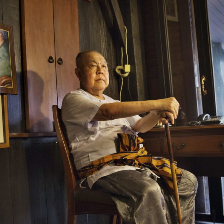 Sulak Sivaraksa, who has been charged or arrested five times under Thailand's lese-majeste law, at home in Bangkok. To the left is a photo of Sulak with the late king, Bhumibol Adulyadej.