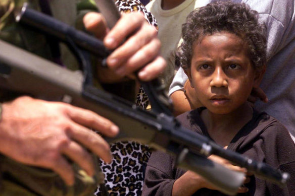 An East Timorese child stares at a passing Australian soldier as peacekeepers and UN officials visited a refugee camp in Dare, East Timor, 21 September 1999. 