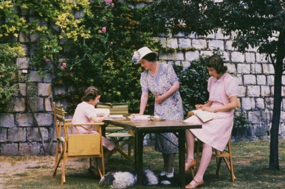 Princesses Elizabeth and Margaret Rose as they work at a desk in the grounds of Windsor Castle, Berkshire in 1941.