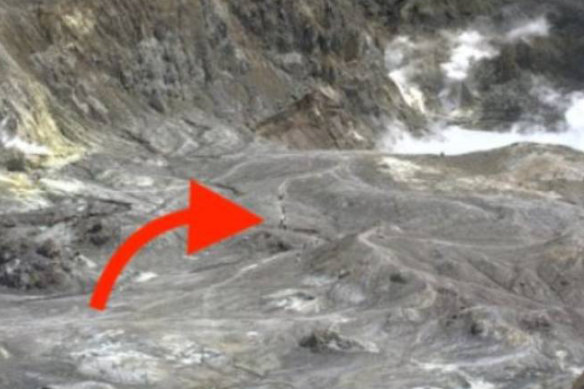 The arrow indicates a line of people walking along a track on White Island, moments before the volcano erupted. 