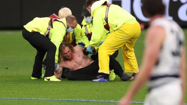 Topless and now jobless: Optus Stadium security subdue pitch invader Jesse Hayen, who was fined $8000 in a Perth court on Friday.