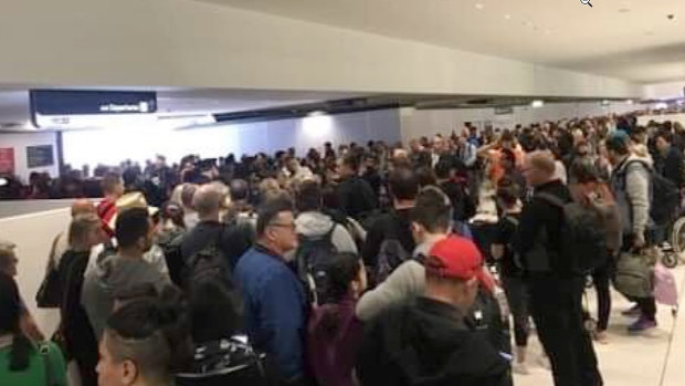 Hundreds of people stand in line at international departures gate because of smoke in the screening area. 