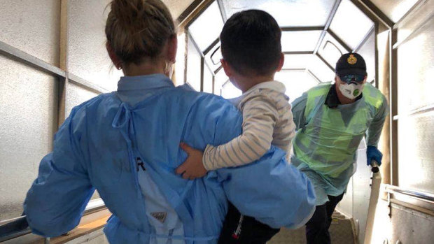 A child is carried from the Qantas evacuation flight at Darwin International Airport on Sunday.