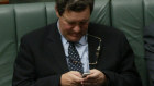 Alexander Downer on his phone during  Question Time when he was in Parliament.