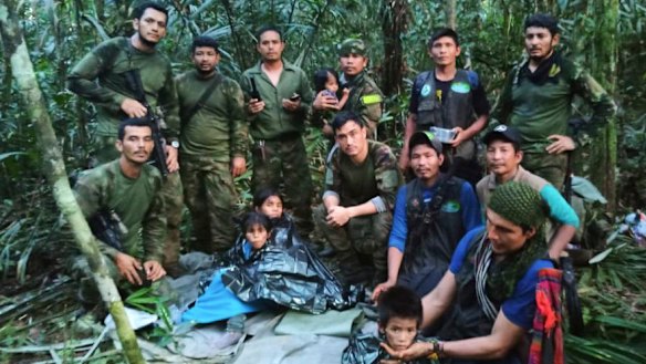 In this photo released by Colombia’s Armed Forces Press Office, soldiers and Indigenous men pose for a photo with the four Indigenous children who were missing after a deadly plane crash.