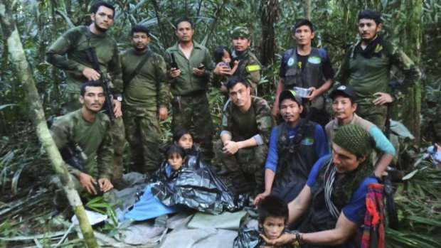 In this photo released by Colombia’s Armed Forces Press Office, soldiers and Indigenous men pose for a photo with the four Indigenous children who were missing after a deadly plane crash.