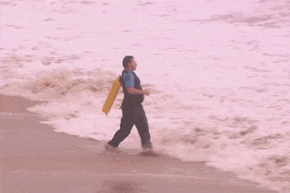 A police officer and another rescuer dive into the ocean at Coogee Beach.