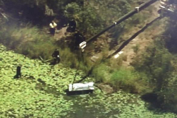 A crane lifts the metal toolbox containing the two bodies from a lagoon in Logan.
