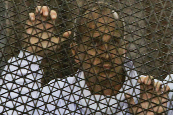 Al Jazeera journalist Peter Greste stands inside the defendants' cage in a courtroom during a trial on terror charges, along with several other defendants, in Cairo Egypt.