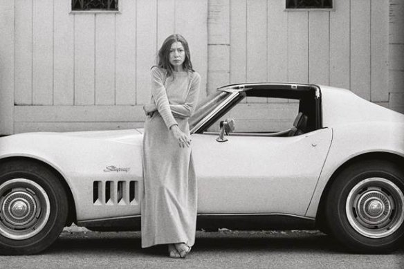 Writer Joan Didion in front of her sports car.