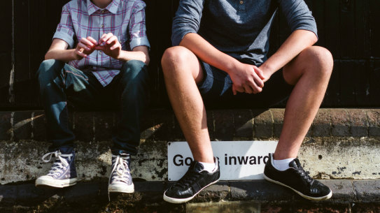 Stock photo of two teenage boys sitting on a wall. 