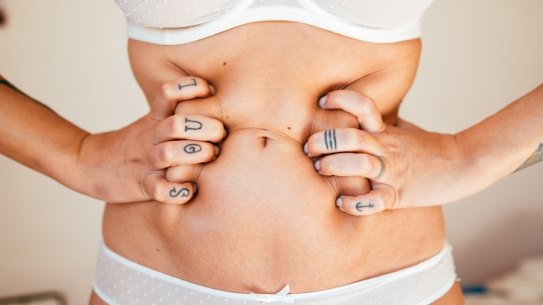 Detail of woman squeezing her belly Woman holding her stomach.?