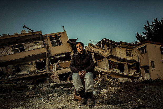 A woman sits in front of her home in Antakya, Turkey, after an earthquake devastated the area in 2023.