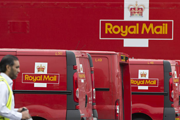 A post office worker walks by Royal Mail vans.