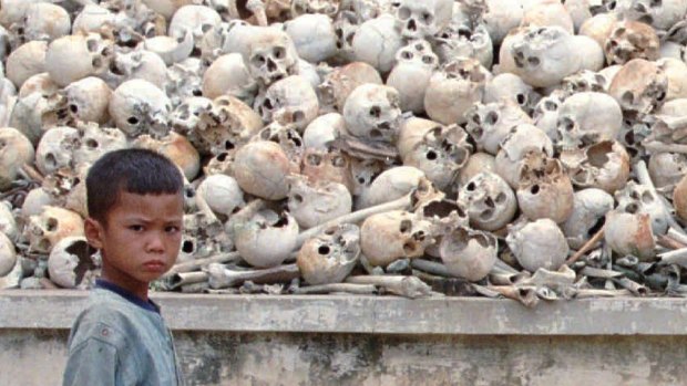 A Cambodian boy stands in front of  human skulls discovered 25 km south of Phnom Penh in 1995. The mass grave contains the remains of about 2000 victims of the Khmer Rouge.