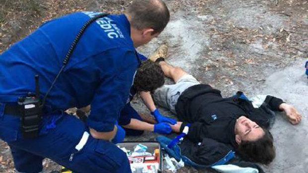 Paramedics attend to Darcy McKay after his bike crashed on a rutted dirt track in Pambula Beach. He used Siri to call triple zero.