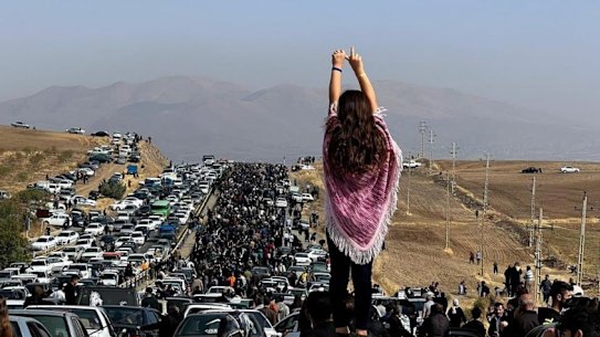 A girl with uncovered head stands atop a car during protests in Iran.