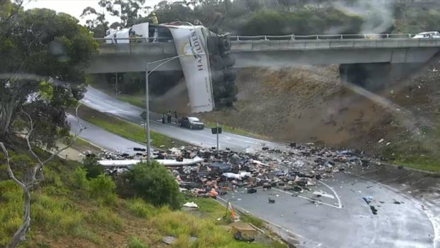 All citybound lanes were closed on the Calder Freeway after a truck rolled, leaving its trailer dangling over the overpass.