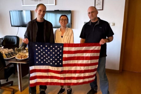 Wall Street Journal Reporter Evan Gershkovich, Radio Free Europe journalist Alsu Kurmasheva, and former U.S. Marine Paul Whelan pose with an American flag in the airport lounge in Ankara, Turkey after being freed.