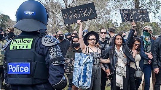A woman at an anti-lockdown rally in Melbourne holds up a sign with the hashtag "#WWG1WGA", which stands for "where we go one, we go all".