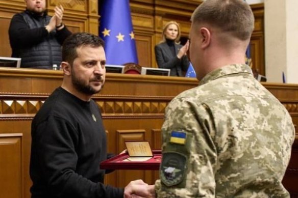 Ukrainian President Volodymyr Zelensky honours a soldier.