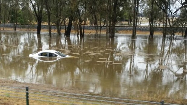 A car is mostly submerged in floodwater on the Hume Freeway. 