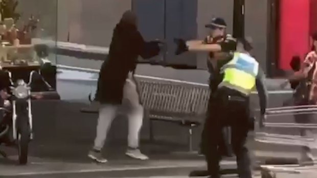Police officers confront Hassan Khalif Shire Ali on Bourke Street. 
