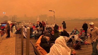 Locals and tourists on the Mallacoota wharf as fire devastated the region over summer.