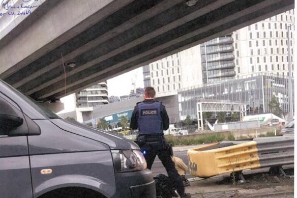 Senior Constable Roland Jones standing with Akiir Muo on the West Gate Freeway on-ramp after she got out of Gargasoulas' stolen car.