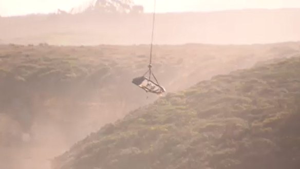 A helicopter winches the wreckage of the lifesaving boat out of the water at Port Campbell on Monday. 