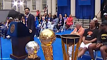 Zoran Mamdani addresses the crowd with Dolan sitting behind him.