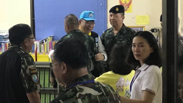 Rescue mission chief Narongsak Osottanakorn (in blue hat) embraces his colleagues. 