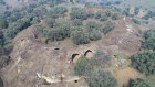 The stone arches that formed the outer walls of the amphitheatre are visible but most of the structure is buried under centuries of soil deposits.